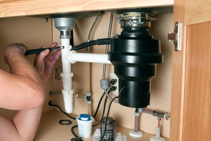 Plumber repairing a garbage disposal in Windsor
