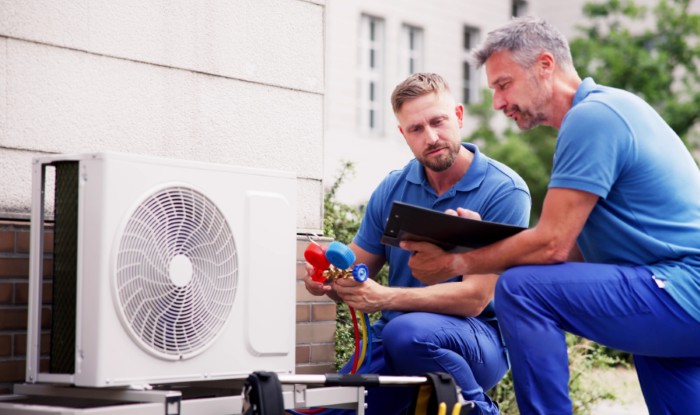 HVAC technicians installing an outdoor air conditioning unit in Windsor