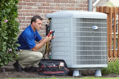 HVAC technician inspecting an outdoor AC unit in Windsor